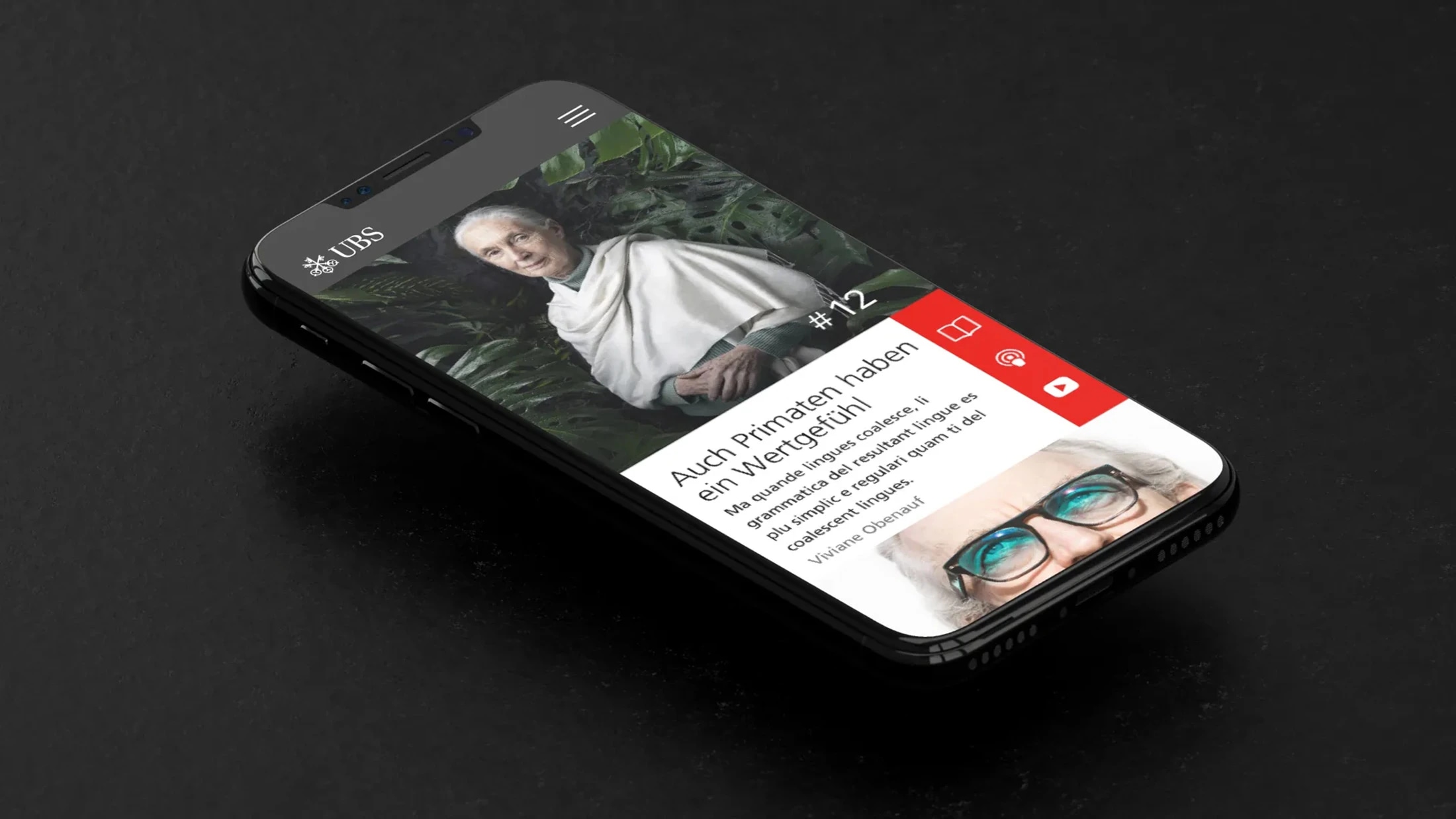 Das Bild zeigt ein Smartphone, das auf einer dunklen Oberfläche liegt und eine App der UBS Bank anzeigt