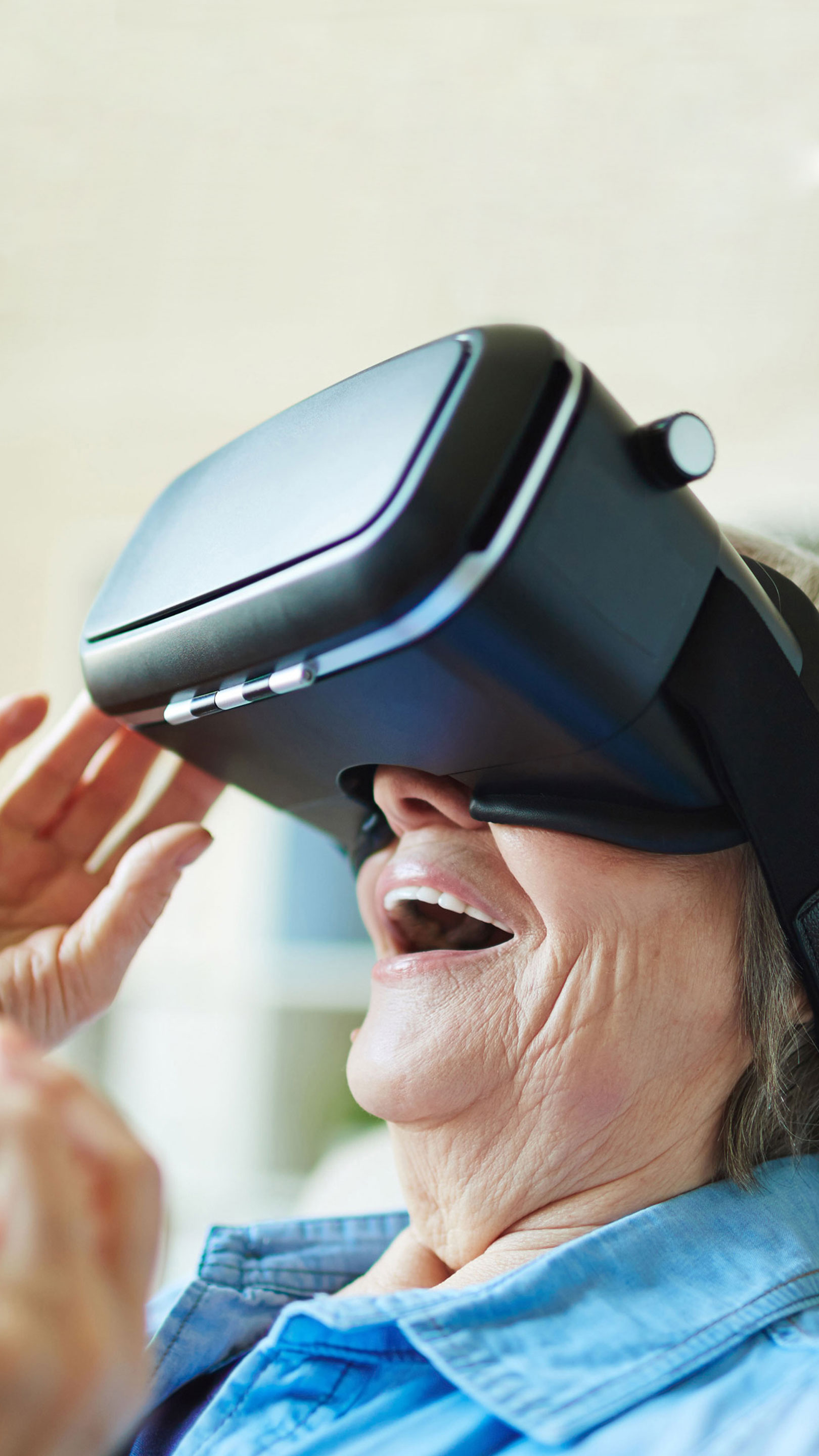 Eine Seniorin benutzt erstaunt eine futuristisch aussehende VR-Brille der Universität Zürich.